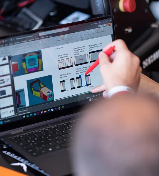 Teammitglied arbeitet an CAD-Modellen des Rennwagens am Laptop