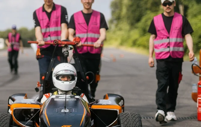 Teammitglieder schieben den Rennwagen auf die Strecke
